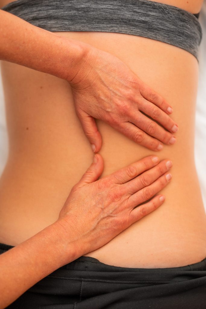 Someone engaging in a reiki healing session, touching the recipient's back.