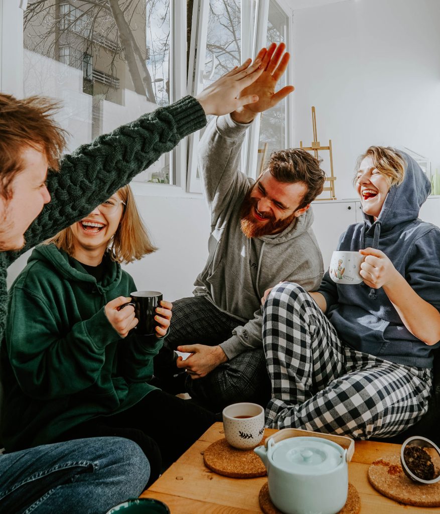 Laughter medicine - friends laughing and high-fiving in a group.